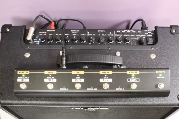 Pedal board laying on top of a guitar amplifier with a green LED indicating that a couple of effects are active, just like it is shown on the amplifier